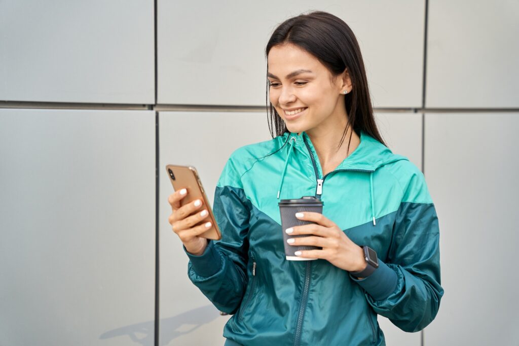 Happy woman in sportswear using mobile phone